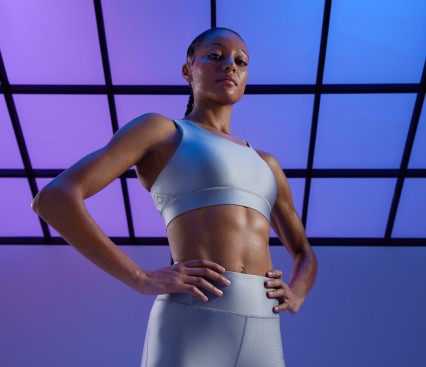 Female athlete in silver workout co-ord posing with hands on hips