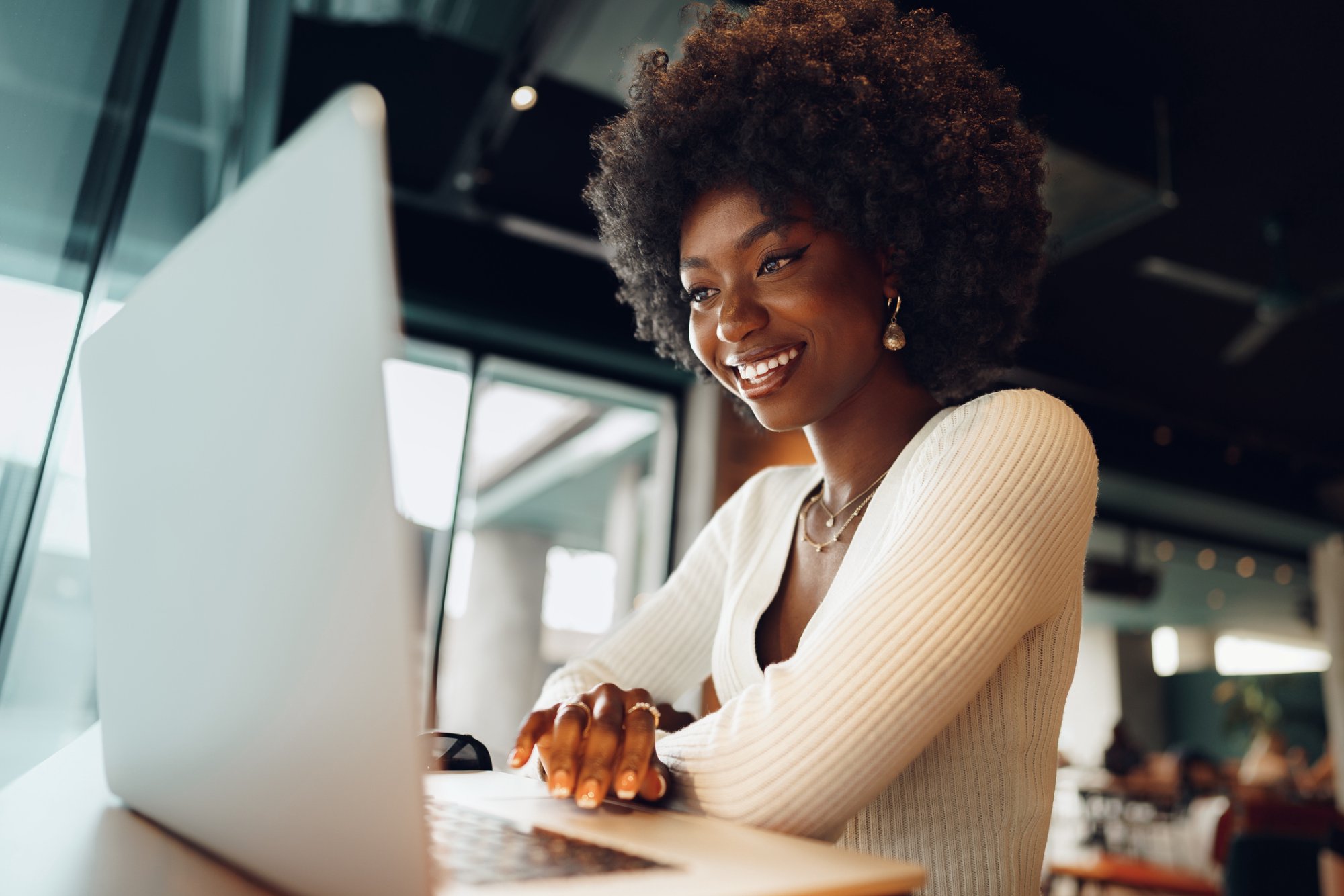 A smiling woman uses a laptop.