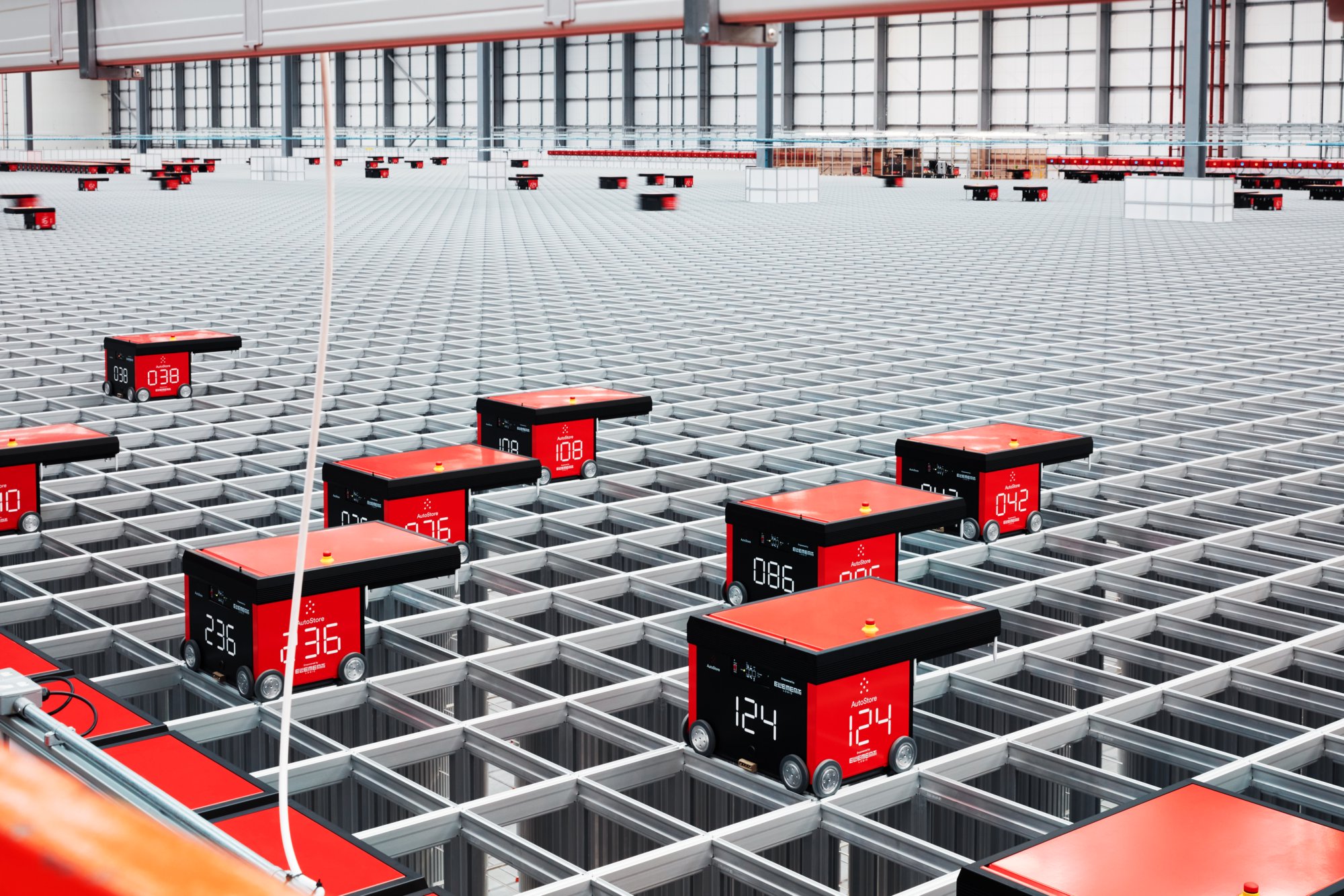 A number of automatic pickers sit atop a grid in a warehouse